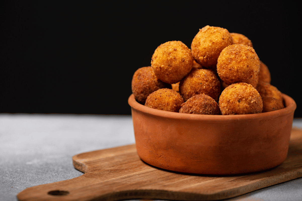 Bolinhas de biscoito cream cracker, servidas em tábua de madeira.