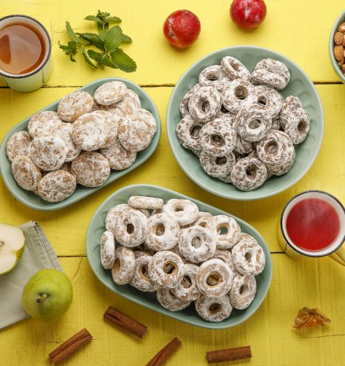Pratos com biscoitos de pão de mel, dispostos ao lado de xícaras de chá.