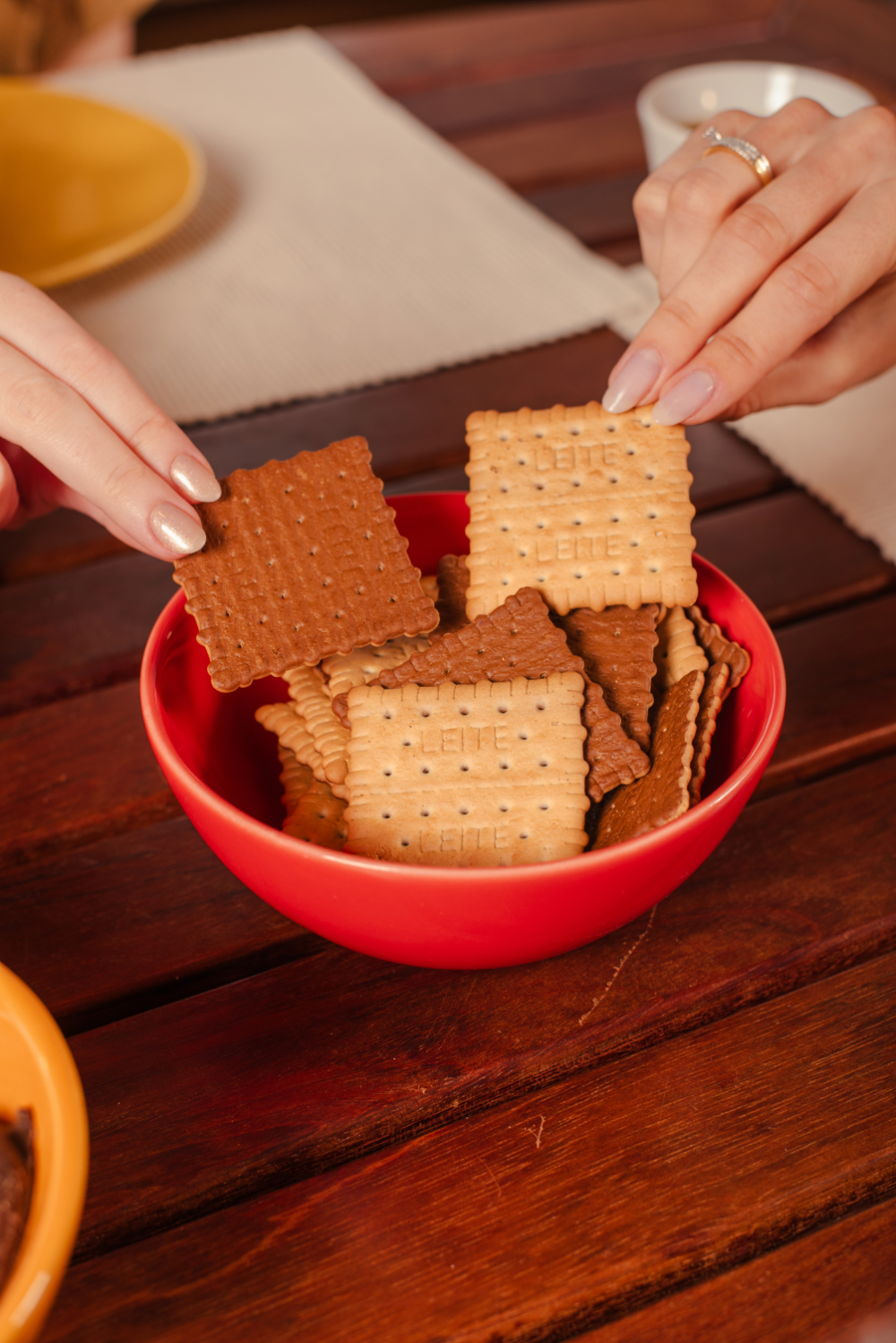Pote vermelho com biscoitos Doble, servidos sobre mesa de madeira
