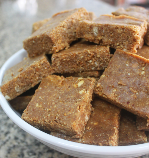 Paçoca com biscoito maisena, servidos em prato sobre fundo desfocado.