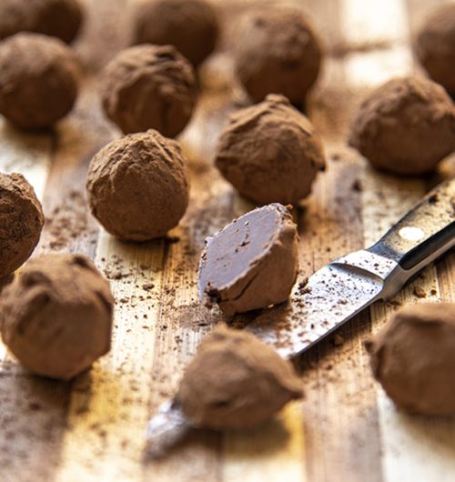 Tábua com trufas de biscoito recheado sabor chocolate, cobertas em cacau em pó.