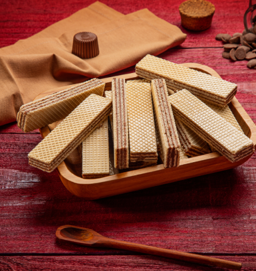 Wafer sabor chocolate suíço dispostos em prato, sobre fundo vermelho.